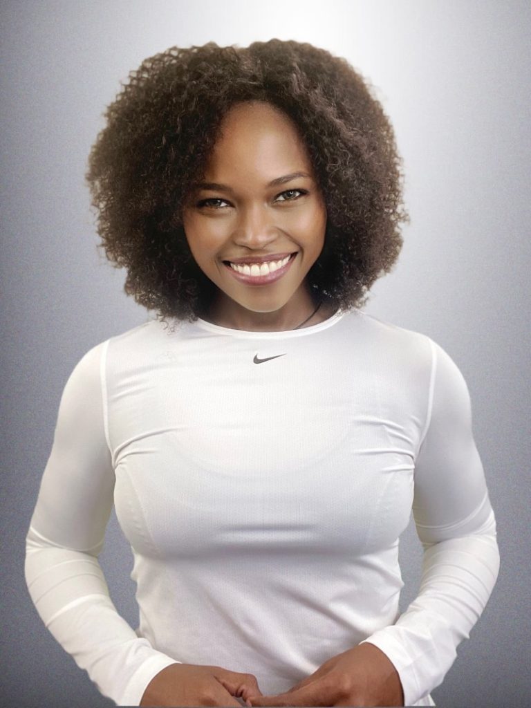A radiant woman with a bright smile, wearing a white athletic top, exudes confidence and positivity.