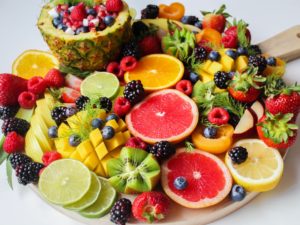 A vibrant and colorful assortment of fresh fruits, including sliced citrus, berries, and tropical varieties, beautifully arranged on a wooden cutting board.