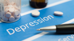 A close-up of medication beside a pen on a paper with the word "depression" indicating a focus on treatment for mental health disorders.