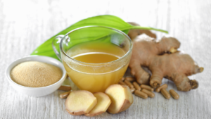 A soothing cup of ginger tea accompanied by fresh ginger root, sliced ginger, herbal capsules, and a bowl of raw sugar, set against a serene backdrop with green leaves.