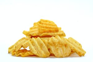 A pile of crispy ridged potato chips on a white background.