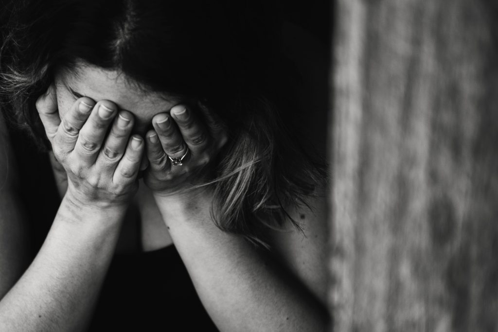 A monochrome image capturing a moment of distress, as a person covers their face with their hands, embodying a poignant expression of sorrow, fatigue, or deep contemplation.