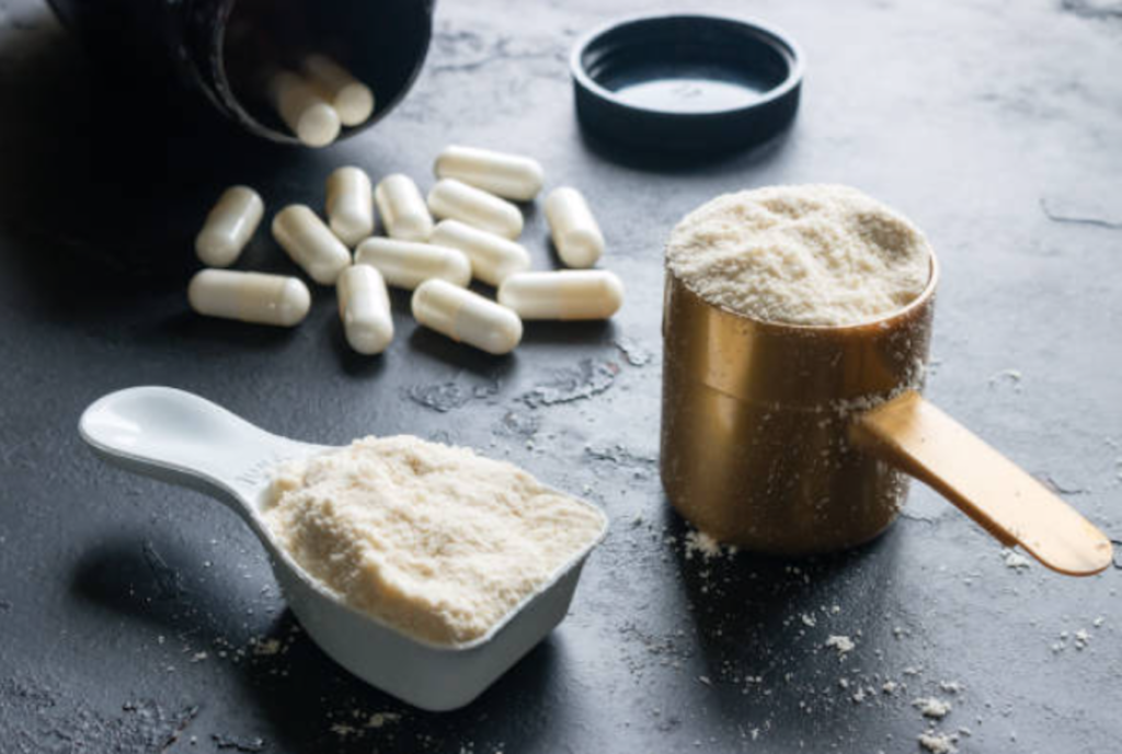 Powdered and encapsulated supplements with a measuring scoop.