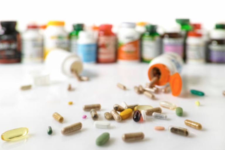 A variety of scattered pills and supplement bottles in soft focus, suggesting a theme of medication use or dietary supplementation.