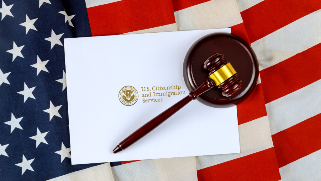 A wooden gavel resting on a white envelope with the U.S. citizenship and immigration services seal, against a backdrop of the American flag, symbolizing the gravity and sometimes depression associated with navigating immigration processes