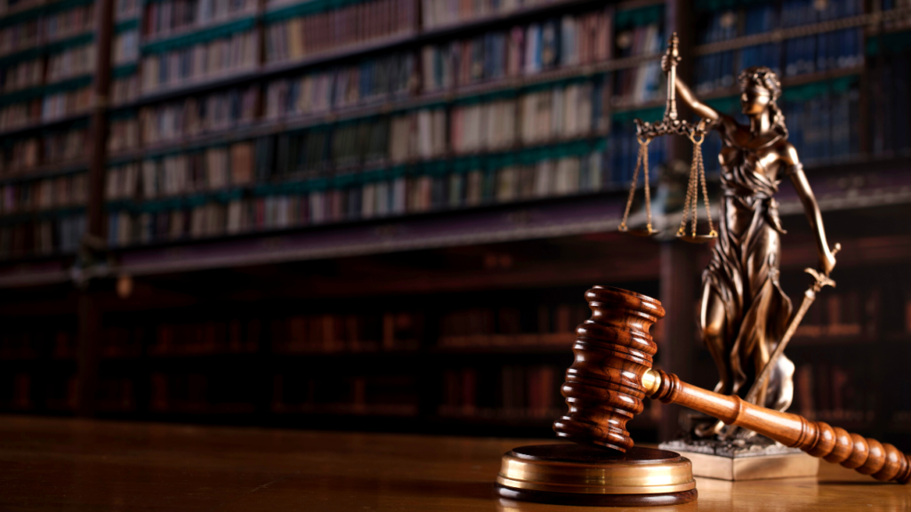 A judge's gavel and the statue of lady justice in the foreground with a blurred background of legal books on shelves, symbolizing the practice of law and the justice system amidst growing concerns over depression within