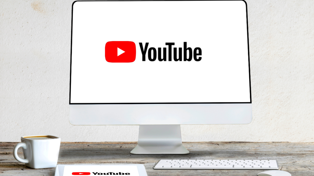 A modern workspace designed to combat depression, featuring a computer displaying the youtube logo on the screen, accompanied by a coffee mug and a notepad with the youtube branding.