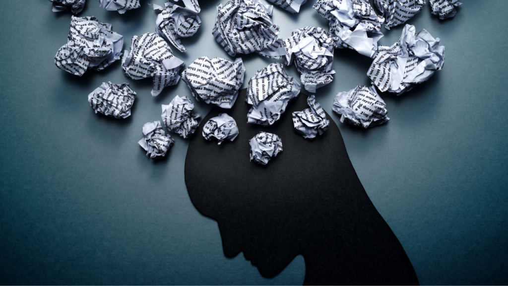 A creative shadow of a head profile surrounded by crumpled paper balls on a blue background, symbolizing overwhelming thoughts, discarded ideas, or depression.