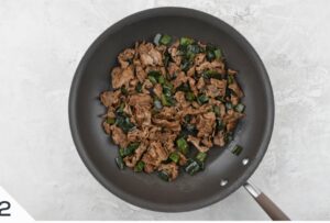 Stir-fried beef and green bell peppers in a non-stick pan, a simple and flavorful dish in the making for queso fondue steak quesadillas.