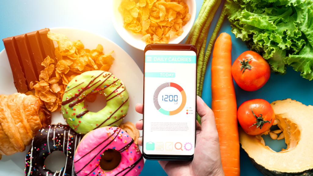 A person holding a smartphone displaying a calorie tracking app, surrounded by a mix of healthy and unhealthy foods, illustrating the concept of diet management and calorie counting.