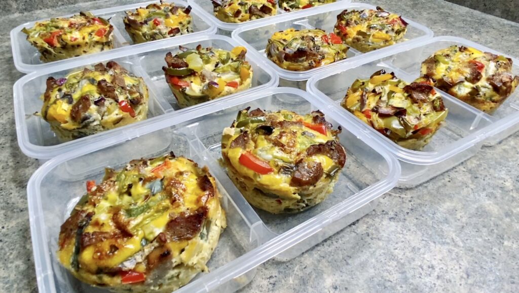 A collection of colorful, vegetable-packed egg muffins arranged neatly in meal prep containers, showcasing a healthy and convenient meal option.