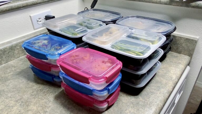 A collection of various colored meal prep containers neatly stacked on a kitchen counter.