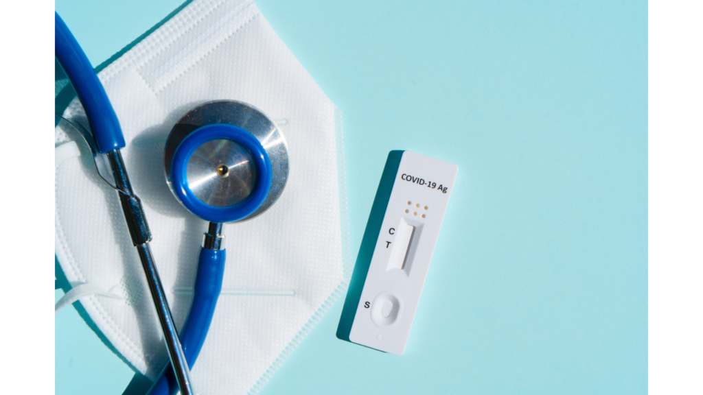 A stethoscope and a mask alongside a negative covid-19 rapid antigen test on a blue background.