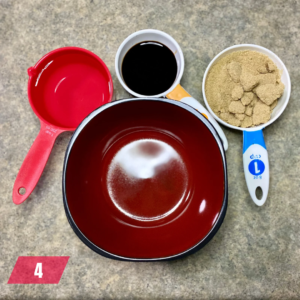 Ingredients for a delicious Mongolian Beef recipe measured out and ready, with a red saucepan, a cup of liquid, and measuring cups of brown sugar and another ingredient.