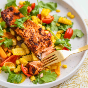 A plate of Vegan Recipes - eBook on a bed of fresh salad with corn, cherry tomatoes, and herbs, with a fork taking a bite, showcasing a healthy and colorful meal.