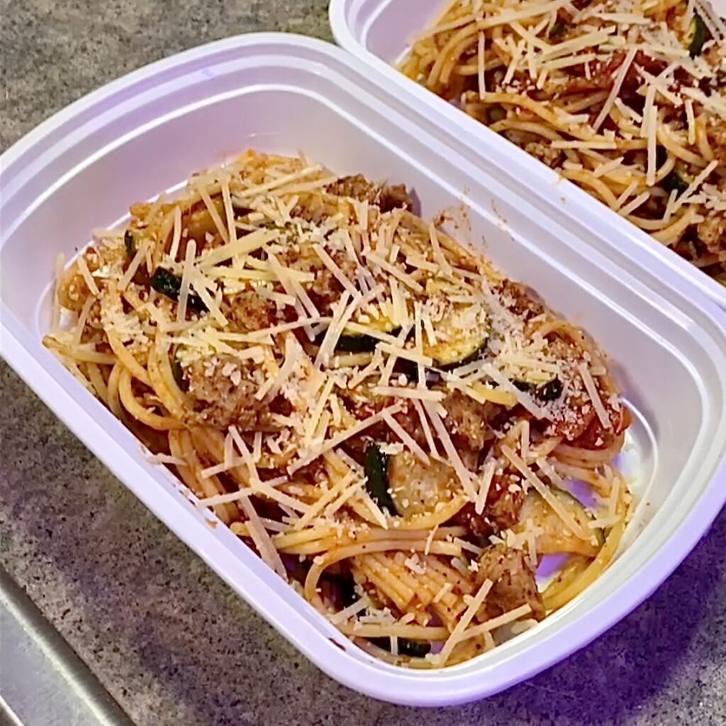 A container of spaghetti topped with grated cheese, ready for a convenient and tasty meal on the go.
