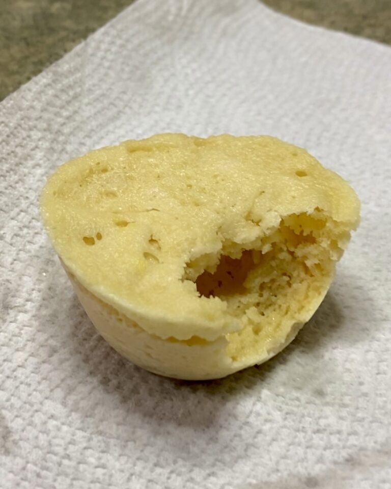 A close-up of a bitten muffin on a paper towel, highlighting its soft, crumbly texture.