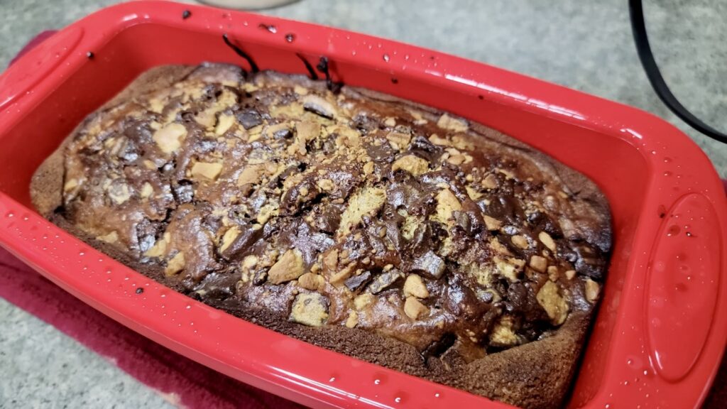 Freshly baked chocolate brownie with nuts in a red baking dish.