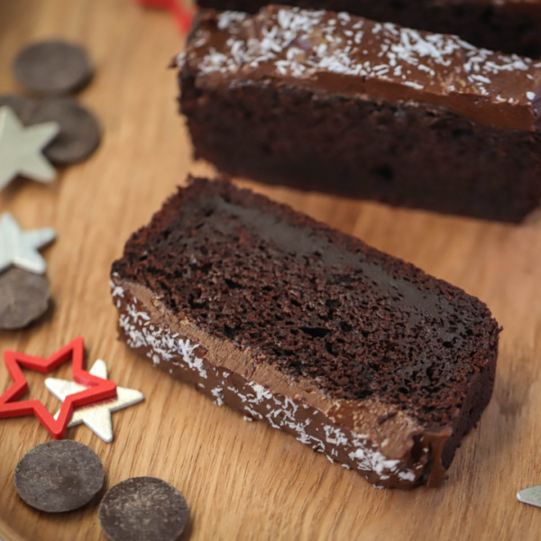 A close-up from the "Holiday Treats [1]" eBook features a chocolate cake slice with icing and coconut flakes, set on a wooden surface, adorned with chocolate chips and red/silver star shapes.