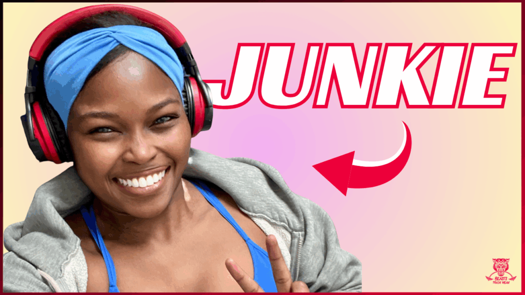 A smiling woman wearing a blue headband and headphones flashes a peace sign. The background is pink and yellow, with "JUNKIE" in bold red letters and a red arrow pointing at her.