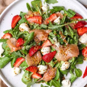 Enjoy a fresh arugula salad with strawberries, mozzarella balls, smoked salmon, and mustard seeds—one of many nutritious dishes you'll find in The New Year Reset Recipe Bundle.