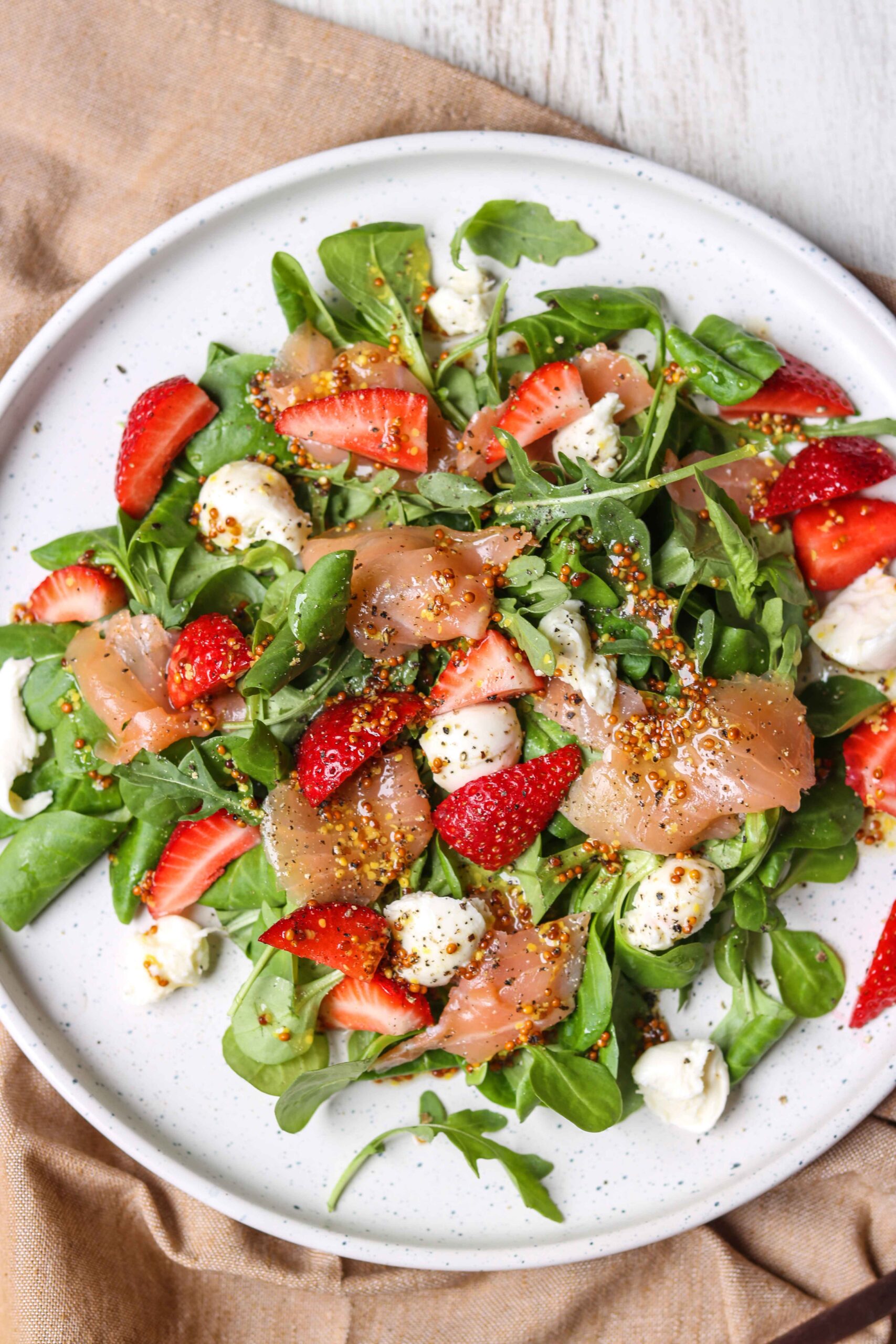 Enjoy a fresh arugula salad with strawberries, mozzarella balls, smoked salmon, and mustard seeds—one of many nutritious dishes you'll find in The New Year Reset Recipe Bundle.